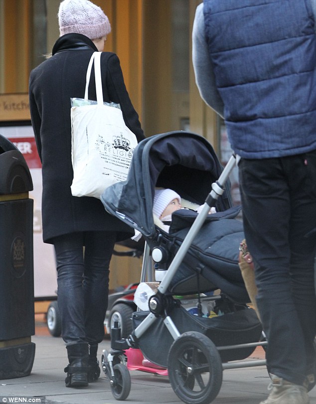 Letting dad do all the hard work: Baby India Rose was chilling in her pram and joined her parents in wearing a cosy hat