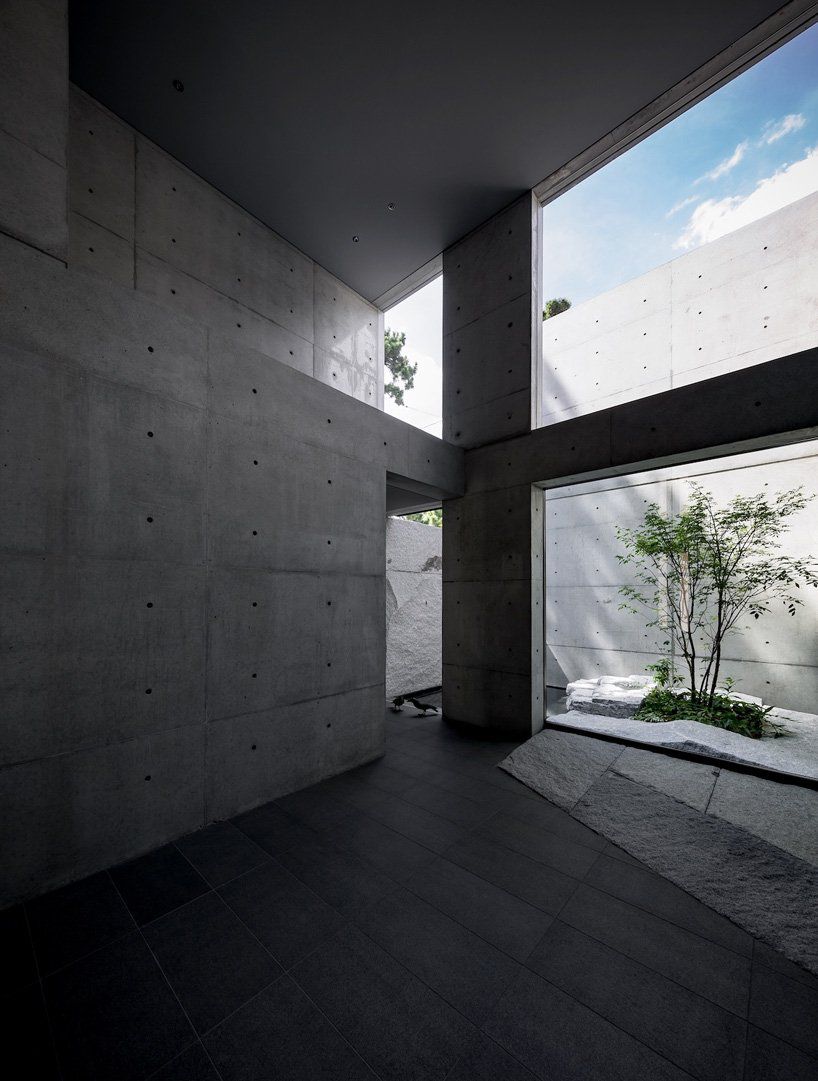 All-concrete room with high ceilings and an opening to an outdoor zen garden. 